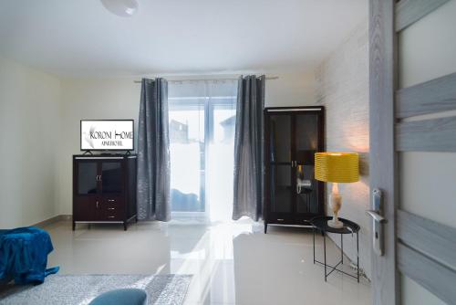 a living room with a lamp and a large window at Aparthotel Koroni Home in Raszyn