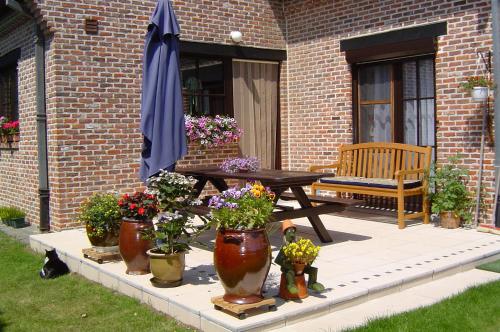 a patio with a table and potted plants and an umbrella at B&B Vanderstraeten-Bryxis in Grimbergen
