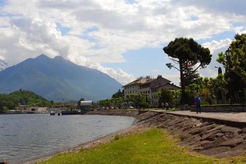 a man standing next to a body of water with a mountain at Hotel Risi in Colico