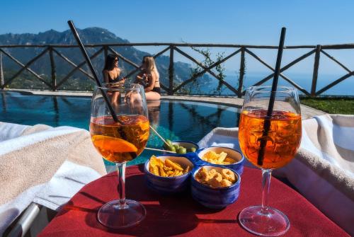 - deux verres de vin et des collations sur une table à côté de la piscine dans l'établissement Garden Hotel, à Ravello
