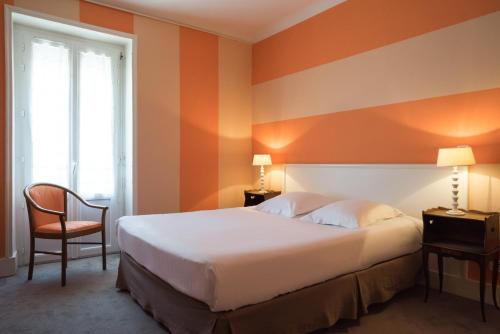 um quarto de hotel com uma cama e uma cadeira em The Originals Boutique, Hôtel Terminus, Bourg-en-Bresse Gare (Qualys-Hotel) em Bourg-en-Bresse