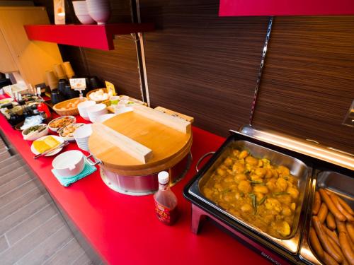 a buffet line with food on a red counter at SUPER HOTEL Tokyo Akabane Station Higashiguchi Ichibangai in Tokyo