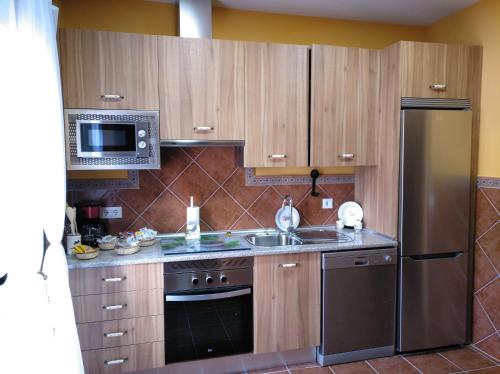 a kitchen with wooden cabinets and a stainless steel refrigerator at Casa Rural La Santiaga in Arroyo de la Luz