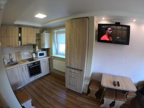 a small kitchen with a television on the wall at Lavander suite in Ventspils