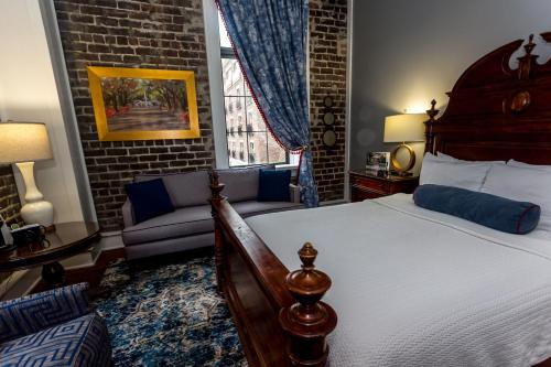 a bedroom with a bed and a couch and a window at East Bay Inn, Historic Inns of Savannah Collection in Savannah