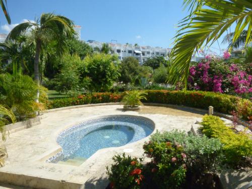 a swimming pool in a garden with flowers at Costa Azul Suites 905 in Santa Marta