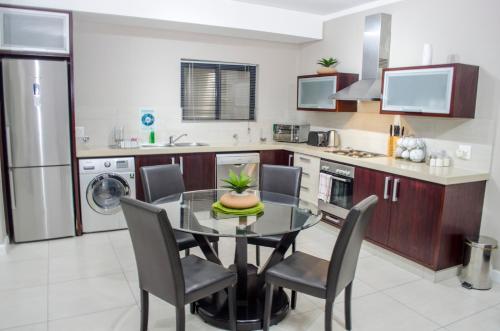 a kitchen with a dining room table and chairs at Knightsbridge Luxury Apartments in Cape Town