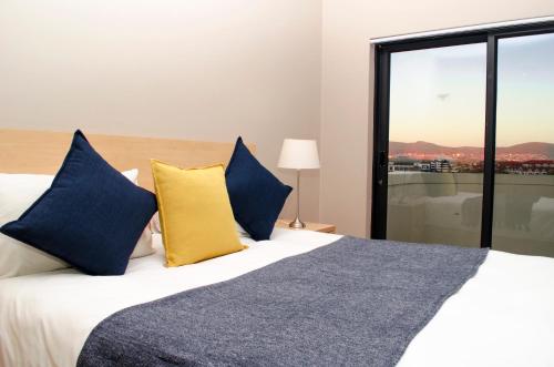 a bedroom with a bed with blue and yellow pillows at Knightsbridge Luxury Apartments in Cape Town