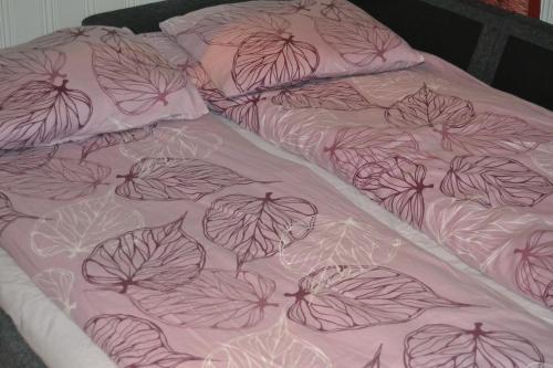 ein Bett mit einer rosa Decke mit Blättern darauf in der Unterkunft Santa´s Studio Valta in Rovaniemi