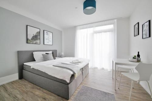 a white bedroom with a bed and a desk at VARIAS Lifestyle Apartments in Elsau