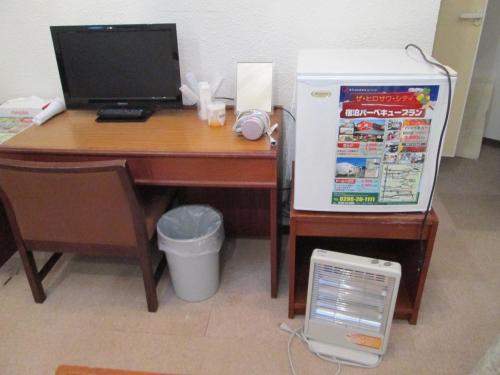 een bureau met een computer en een tafel met een koelkast bij The Hirosawa City Dome House West Building / Vacation STAY 7780 in Chikusei
