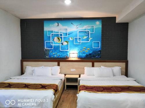2 camas en una habitación con un cuadro en la pared en Mega Inn, en Kuching