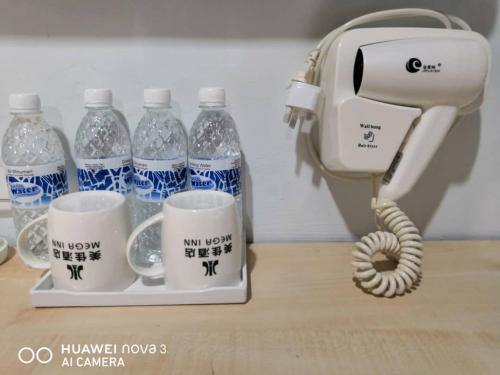 a phone and two cups of water on a counter at Mega Inn in Kuching