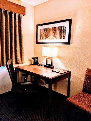a hotel room with a desk with a lamp and a chair at AmericInn by Wyndham Grand Forks in Grand Forks