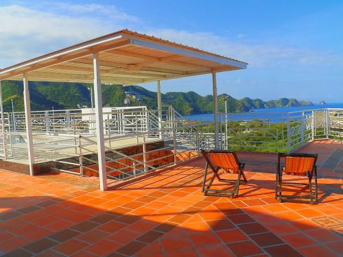 two chairs sitting on a patio with a pavilion at Hostel Green Light in Taganga