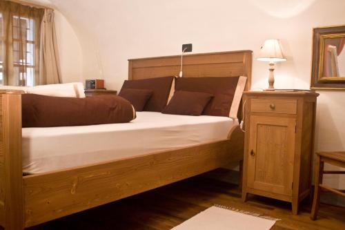 a wooden bed with white sheets and brown pillows at Contrada Beltramelli in Villa di Tirano