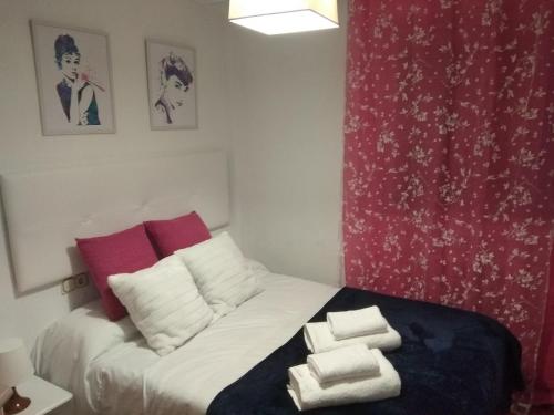 um pequeno quarto com uma cama com almofadas vermelhas e brancas em VuT EL GRECO em Salamanca