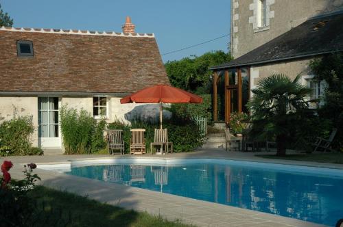 a house and a swimming pool with an umbrella at Le Chat Courant in Villandry