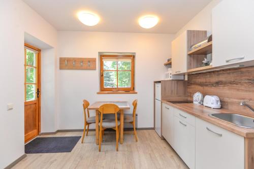 a kitchen with a table and chairs and a sink at Apartamentai Gėlių Vila in Nida