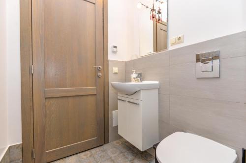 a bathroom with a toilet and a sink and a door at Apartamentai Gėlių Vila in Nida