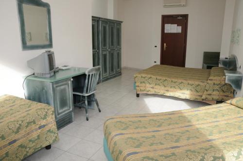 a room with three beds and a desk and a tv at Hotel Meridiana in Arbus