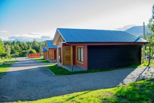 a house with a garage next to a road at Cabañas Cerro Huemules in Coihaique