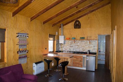 a kitchen with a counter and stools in a room at Cabañas Cerro Huemules in Coihaique