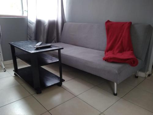 a couch with a red blanket sitting next to a table at Beulahland Guesthouse in Kuilsrivier