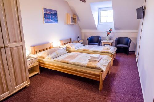 a bedroom with two beds and two chairs at Penzion U Candru in Vyšší Brod