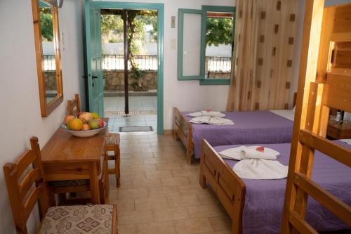 a room with two beds and a table with a bowl of fruit at Dimitris Villa Hotel in Matala