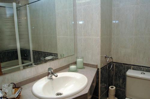 a bathroom with a sink and a mirror and a toilet at Hostal Stop in Cantalejo