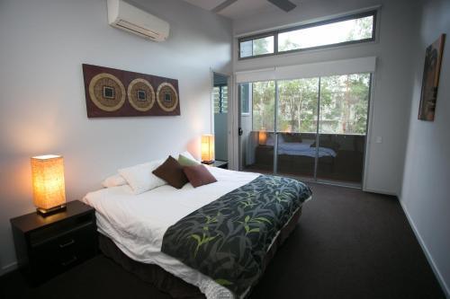 a bedroom with a bed and a large window at The Sanctuary in Noosa North Shore