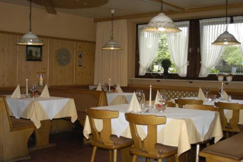 a restaurant with white tables and chairs and windows at Gasthaus Kellerer in Raubling