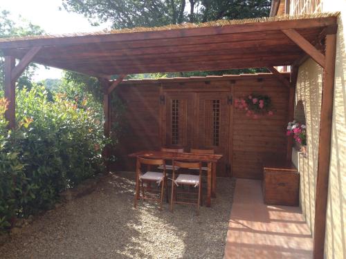 a wooden pergola with a wooden table and chairs at CasaJona Holiday in Poggibonsi