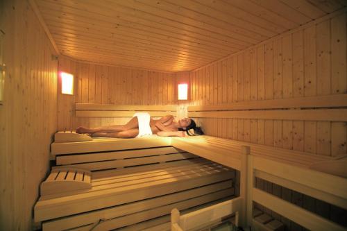 a woman is laying in a sauna at Hotel Kronplatz in Valdaora