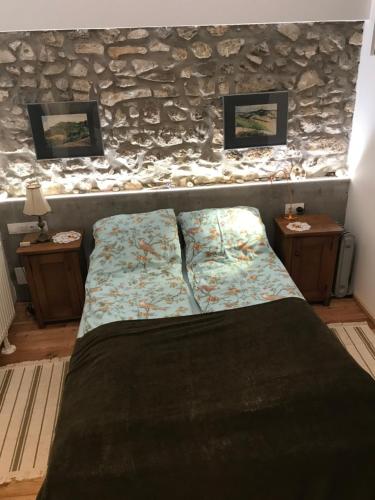a bed in a room with a stone wall at Patak Apartman, Diszel in Tapolca