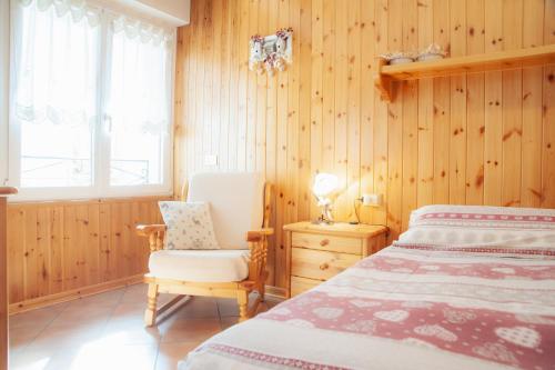 a bedroom with a bed and a chair and a window at Casa Scalet in Fiera di Primiero