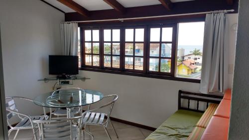una mesa de cristal y sillas en una habitación con ventana en Apartamentos Morada Aquitânia, en Bombinhas