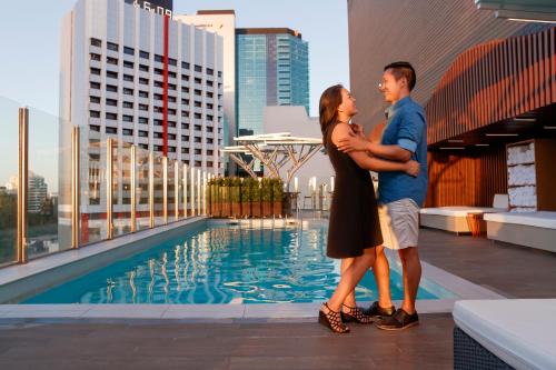 a couple standing on top of a building with a pool at Pullman Brisbane King George Square in Brisbane