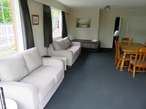 a living room with white couches and a table at Admirals Motor Lodge in Blenheim
