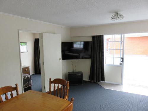 a dining room with a table and a tv on the wall at Admirals Motor Lodge in Blenheim