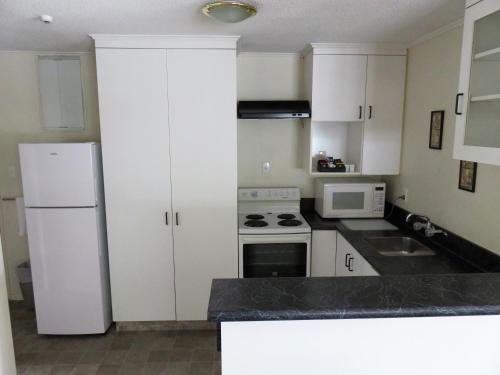 a kitchen with white cabinets and a white refrigerator at Admirals Motor Lodge in Blenheim
