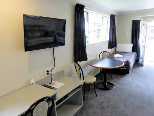 a living room with a table and a tv on the wall at Admirals Motor Lodge in Blenheim