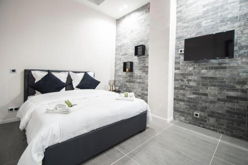パリにあるDreamyflat - Loft Louvreのレンガの壁にテレビと大型ベッドが備わるベッドルーム1室が備わります。