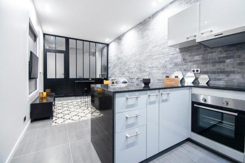 une cuisine avec des placards blancs et un mur en briques dans l'établissement Dreamyflat - Loft Louvre, à Paris