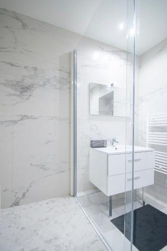 une salle de bain blanche avec un lavabo et une douche dans l'établissement Dreamyflat - Loft Louvre, à Paris