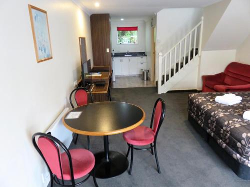 a room with a table and chairs and a bed at Admirals Motor Lodge in Blenheim