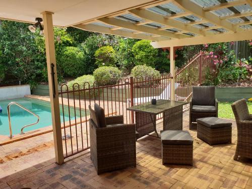 a patio with a table and chairs next to a pool at Robyn's Nest - Bed and Breakfast in Tewantin