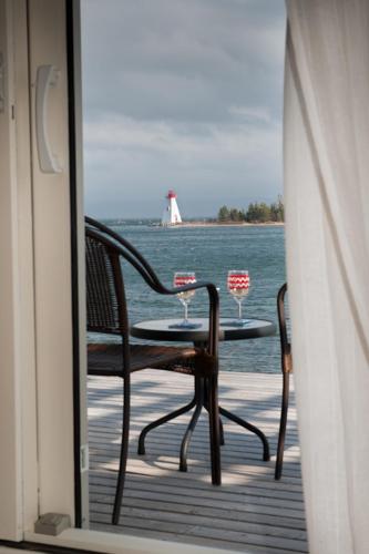 a table and chairs on a deck with a view of the water at Dunlop Inn in Baddeck