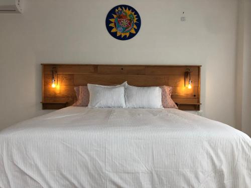 uma grande cama branca com duas almofadas e um relógio na parede em Las grutas Punta del este em Punta del Este